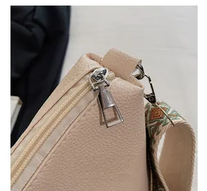 Detail of the litchi grain bag with zipper closure and geometric patterned strap