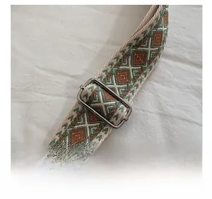 Detail of adjustable geometric strap with olive and brown woven patterns and silver buckle