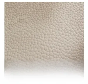 Detailed macro view of the premium beige lychee pattern leather texture on a tote bag