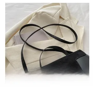 Detail of adjustable strap with gold metal buckle on a black leather and suede bag