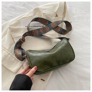 Detail der vintage grünen PU-Leder Mondtasche mit geometrisch gewebtem Gurt