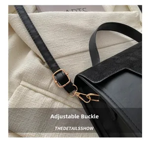 Detail of black suede bag showing golden adjustable buckle and mixed leather textures
