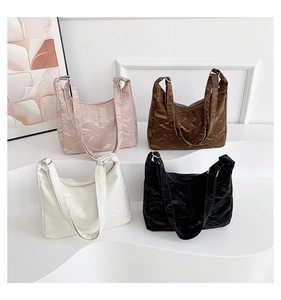 Détail de quatre sacs à main colorés en cuir verni plissé sur un présentoir blanc chic