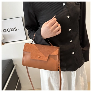 Detailed texture of brown suede and smooth leather on a stylish crossbody bag