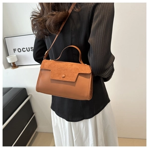Detail of a brown suede and leather crossbody bag shown on a model for scale and style
