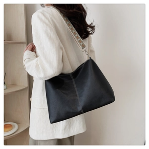 Close-up of black leather tote with white stitching and retro jacquard wide shoulder strap