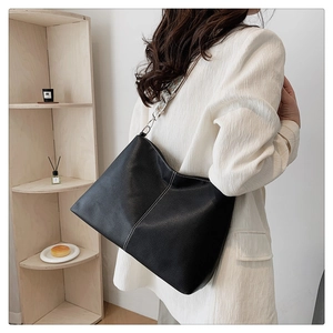 Detail of black pebbled leather tote with white stitching and a geometric wide strap