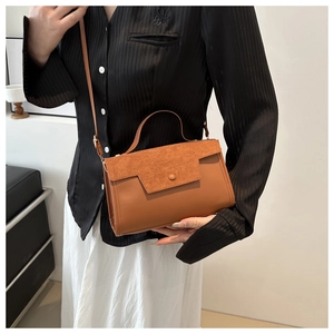 Side view of a brown suede and leather patchwork crossbody bag worn by a model
