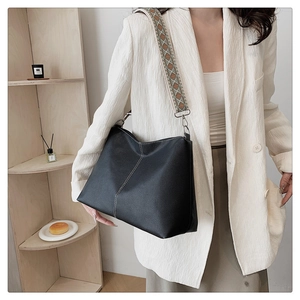 Detail of black pebbled leather tote with contrast stitching and ethnic pattern strap