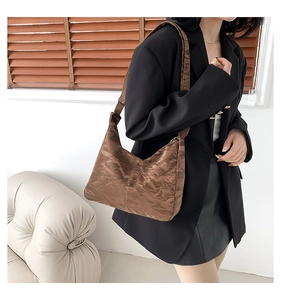 Sac hobo marron à texture plissée brillante porté par un mannequin en intérieur