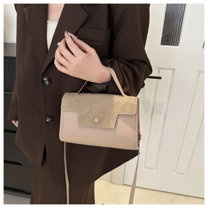 Detailed shot of beige suede patchwork handbag held by a model in a brown blazer
