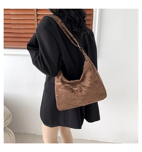 Sac hobo marron plissé à texture brillante porté par un mannequin dans un décor épuré