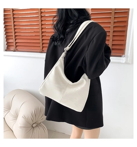 Détail du sac fourre-tout crème en cuir PU avec bandoulière nouée porté par un mannequin