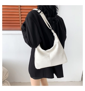 Sac à bandoulière blanc minimaliste en forme de croissant porté par un mannequin