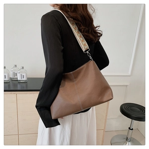 Brown lychee leather tote bag featuring a colorful geometric jacquard wide shoulder strap