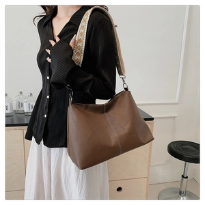 Detail of coffee brown pebble leather tote with colorful geometric woven wide strap