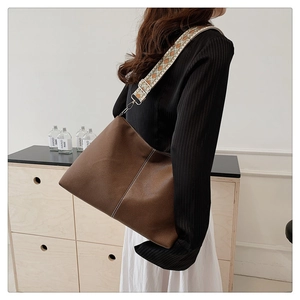 Brown leather tote bag featuring a vintage ethnic wide strap and litchi texture