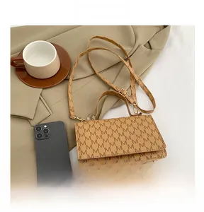 Close-up of khaki leather crossbody bag featuring letter monogram and flip-top closure