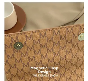 Detail of magnetic snap closure on monogram brown leather handbag with pebble texture