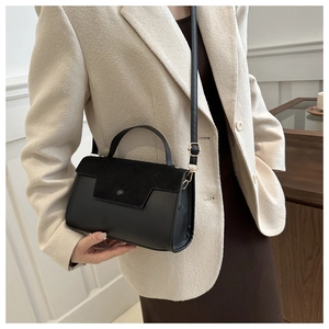 Detail of black matte suede crossbody bag styled with a beige blazer for a retro look