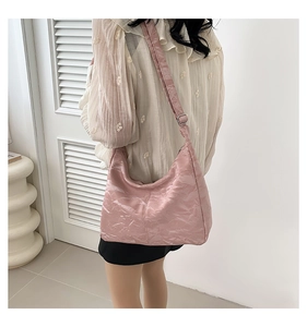 Détail du sac à bandoulière rose avec texture plissée brillante et forme de demi-lune