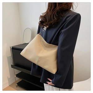 Detail of beige hobo bag with wide shoulder strap and silver hardware on a model