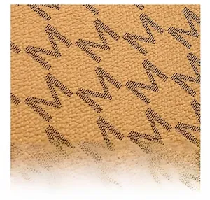 Macro view of textured brown lychee leather with black dotted letter M pattern print