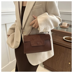 Close-up of vintage brown crossbody bag with suede flap and round button on cafe counter