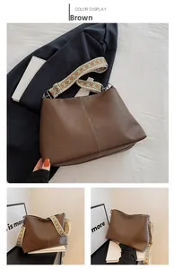 Close-up of brown leather bucket bag featuring a vibrant ethnic geometric wide strap