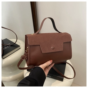 Detail of brown faux suede and leather handbag with gold buckles and adjustable strap