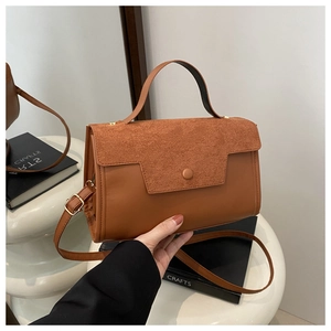 Detail of caramel brown suede and leather stitching with gold hardware on a handbag