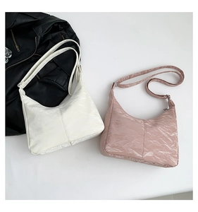 Détail de sacs à bandoulière demi-lune en cuir verni plissé, en couleurs blanc et rose poudré