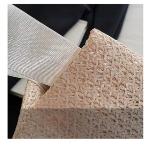 Close-up of the woven texture and fabric strap attachment on the straw tote bag