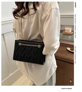 Quilted black leather shoulder bag with V-shaped embossing and golden chain strap detail