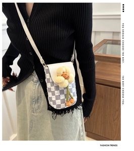 Close-up of checkerboard knit phone bag with 3D yellow flower and soft shoulder strap