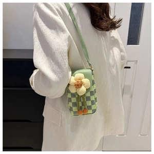 Detail of green checkered fabric phone bag with yellow knitted flower on a white blazer