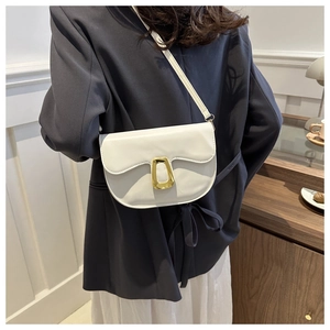 Detail of a white leather saddle bag with gold metal clasp on a model's shoulder
