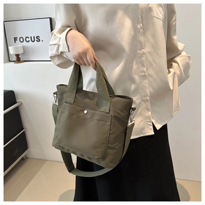 Detail of army green nylon tote bag featuring silver snap button pocket and wide web straps