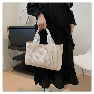 Close-up of tight weave straw tote bag featuring wide fabric handles and large capacity