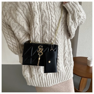 Detail of black quilted leather shoulder bag with gold hardware and tassel charm