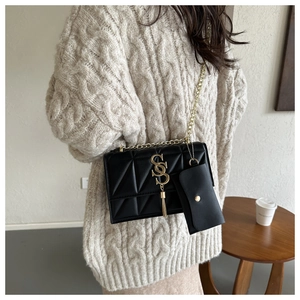 Detail of black quilted chain bag with gold logo, tassel, and matching coin purse