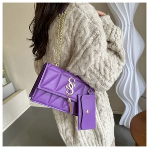 Detail of purple quilted chain bag with fringe charm and removable coin purse on beige sweater