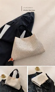 Detail of handwoven straw tote bag featuring contrast black straps and cream woven texture