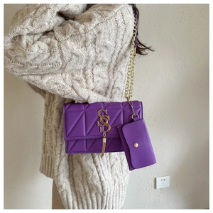 Detail of purple quilted shoulder bag with gold chain strap, tassel and small coin purse