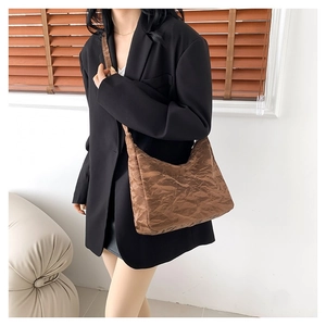 Sac hobo marron plissé au fini brillant pour femme dans un intérieur au style épuré