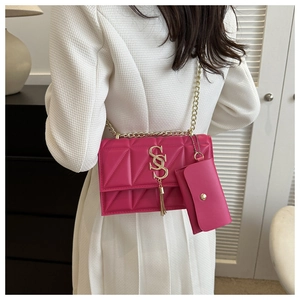 Detail of rose pink quilted chain bag with tassel pendant and gold logo worn by model