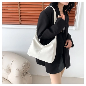 Sac bandoulière demi-lune en cuir verni blanc porté par un mannequin en décor chic