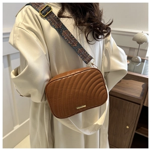 Détail de la bandoulière jacquard élégante sur un sac matelassé marron tendance