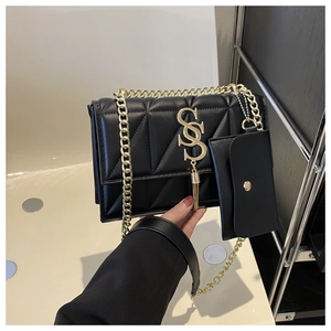 Detail view of black quilted crossbody bag with gold metal buckle and small coin pouch