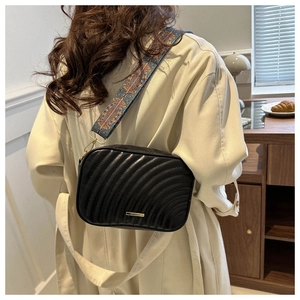Détail du sac bandoulière matelassé noir avec une large sangle brodée ethnique